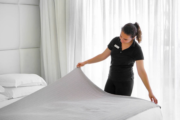 Služebná tvorby posteli v hotelovém pokoji. Hospodyně Making postel. - Fotografie, Obrázek
