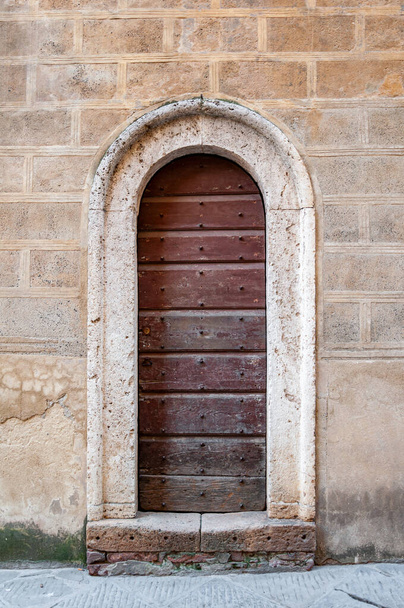 Pienza in Tuscany, Italy. View of an architectural detail with ancient wooden door. UNESCO heritage village, famous for the "Pecorino di Pienza" cheese. - Fotoğraf, Görsel