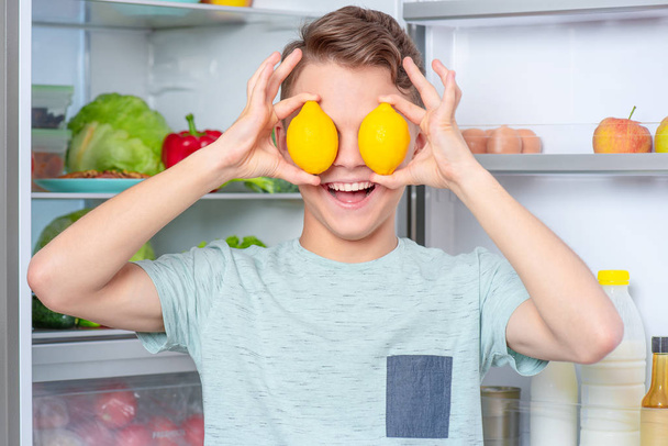 Хлопчик з їжею біля холодильника
 - Фото, зображення