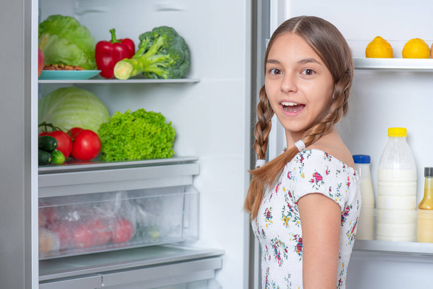 Girl with food near fridge - Fotó, kép