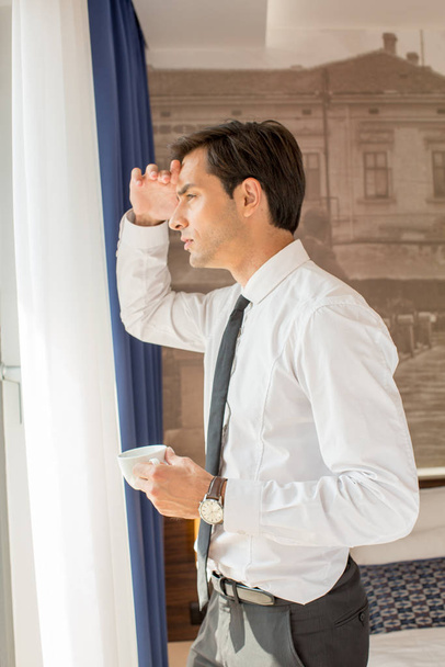 schöner junger Geschäftsmann trinkt Kaffee vor dem Hotel - Foto, Bild