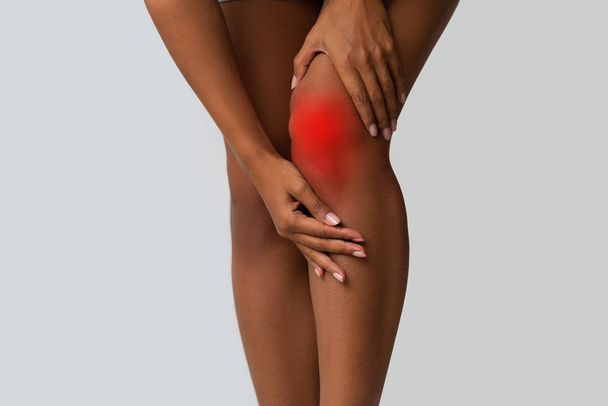 Recortado de negro chica tocando su lesionado rodilla
 - Foto, imagen
