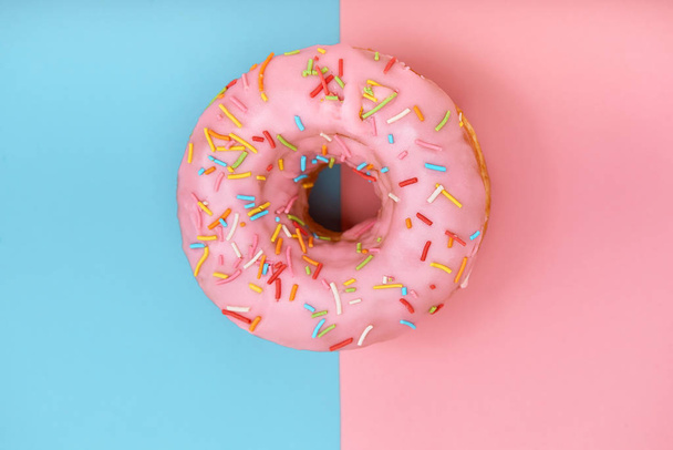Pink donut on pink-blue background, minimalism concept, color play. Pink t blue background, copy space, shot from above. Different looks of one unit. - Foto, Bild
