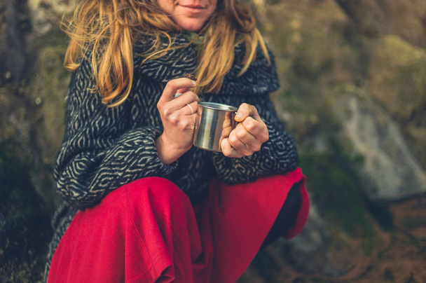 A cold woman is drinking a cup of tea on the beach in winter - Foto, immagini