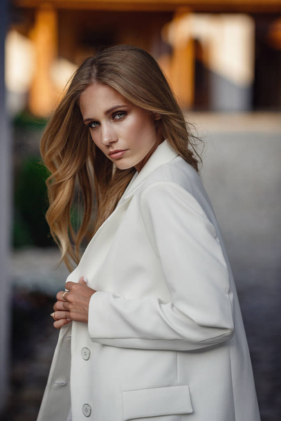 Outdoor full body fashion portrait of fashionable woman in white suit posing in street of east city - Foto, afbeelding