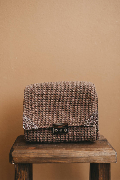 Modna torba na drutach, wykonana z nylonowej nitki, znajduje się na drewnianym krześle. Ręcznie robiony wzór. - Zdjęcie, obraz