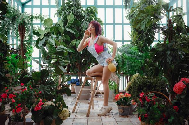 Beautiful young woman works in a greenhouse or in a closed conservatory. - Photo, Image