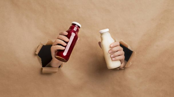 Hands holding detox drinks over cardboard background - Photo, Image
