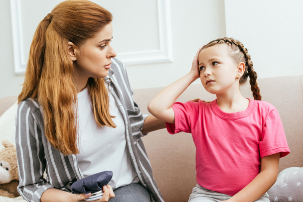 worried mother with ice bag compress talking to daughter with headache - Φωτογραφία, εικόνα