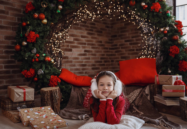Beautiful little girl in red pajamas in the room on a Christmas morning - Photo, Image