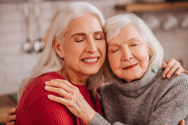Two mature grey-haired positive ladies hugging each other - Foto, immagini