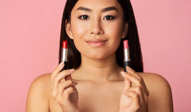 Concept de maquillage. Asiatique fille tenant deux rouges à lèvres
 - Photo, image