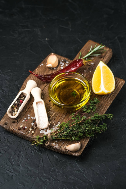 Selected ingredients for cooking. Lemon, herbs, olive oil and spices on a cutting board on a dark stone background.  Top view copy space. - 写真・画像