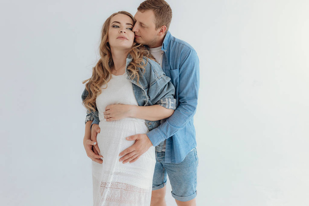 Shot of pretty young pregnant couple in the white room at home. - Foto, afbeelding
