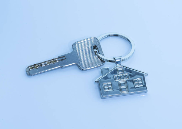 breloczek z symbolem domu i klawiszy na niebieskim tle, Koncepcja nieruchomości - Zdjęcie, obraz