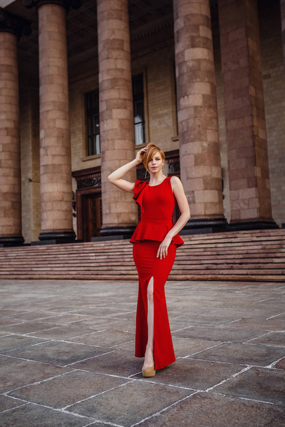 Elegáns nő hosszú piros ruhában és magas sarkú, marad a lépcsőn - Fotó, kép