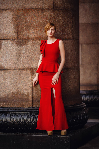 Mujer elegante en vestido rojo largo y tacones altos, permaneciendo en la escalera
 - Foto, Imagen
