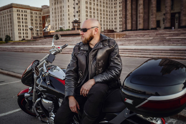 Brutal man on a cool motorcycle against beautiful stately buildi - 写真・画像
