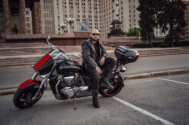 Brutális ember egy hűvös motorkerékpár ellen gyönyörű impozáns épület - Fotó, kép