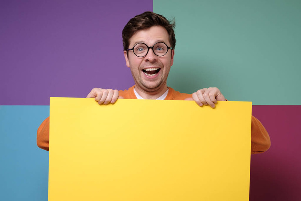 schöner Kerl mit Brille, der leeren gelben Kopierraum zeigt - Foto, Bild