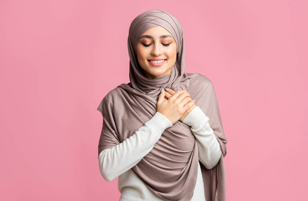 Chica musulmana agradecida manteniendo ambas palmas en el pecho, expresando aprecio
 - Foto, imagen