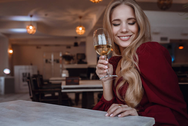 Tyylikäs nainen lasillisella viiniä yksin ravintolassa
 - Valokuva, kuva