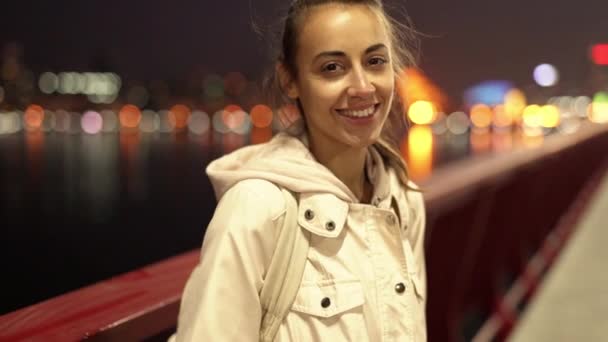 Close-up slowmotion van mooie glimlachende jonge vrouw wandelen buiten nacht stad. - Video