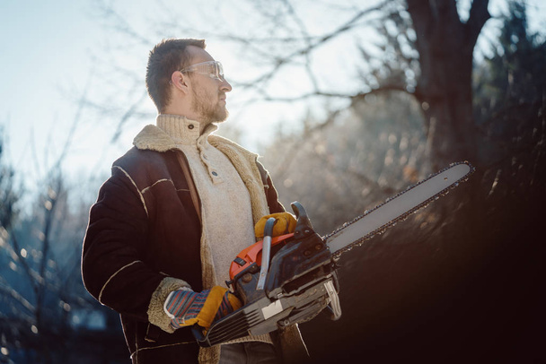 Homme avec une tronçonneuse debout dans les bois prêt à commencer le travail
 - Photo, image