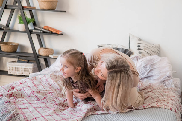 mother and daughter jumping on bed, having fun together - Valokuva, kuva