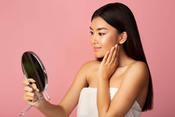 Personal care. Asian girl holding mirror and admiring herself - Photo, Image