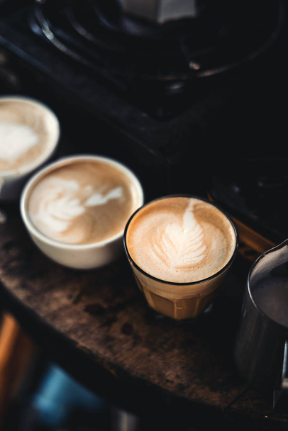 Latte art καφέ σε ένα φλιτζάνι το πρωί σκοτεινό τόνο - Φωτογραφία, εικόνα