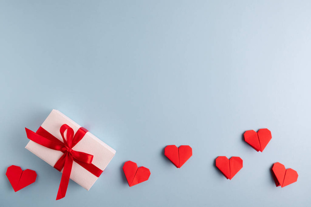 パステルブルーの背景に赤い折り紙の心。バレンタインデーのシンボルデザイン。テキストのためのスペースと紙の装飾。最小限のバレンタインデーのコンセプト. - 写真・画像