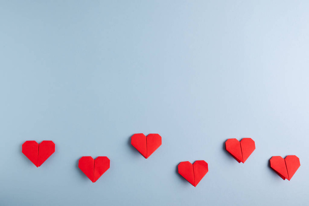 Liebestag. handgefertigte rote Origami-Herzen auf blauem Hintergrund. Ansicht von oben. - Foto, Bild