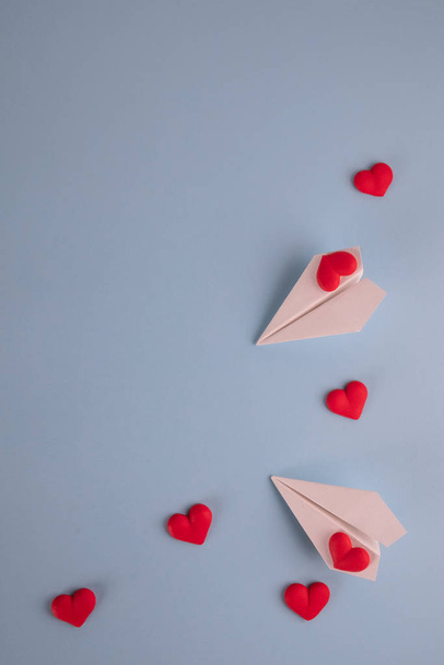 バレンタインデーの背景。パステルブルーの背景に赤いキャンディハートと紙飛行機。バレンタインデーのコンセプト。フラットレイアウト、トップビュー、コピースペース - 写真・画像