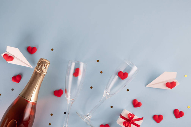 Valentine's Day background. Gift box , alarm clock , red candy  hearts and paper plane, two champagne glasses on pastel blue background. Valentines day concept. Flat lay, top view, copy space - Fotoğraf, Görsel