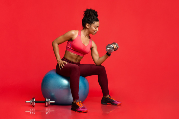 Fitness model pompen strijkijzer, zittend op fitness bal - Foto, afbeelding