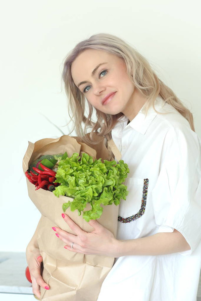Nuori positiivinen hymyilevä nainen vihanneksia keittiössä
 - Valokuva, kuva