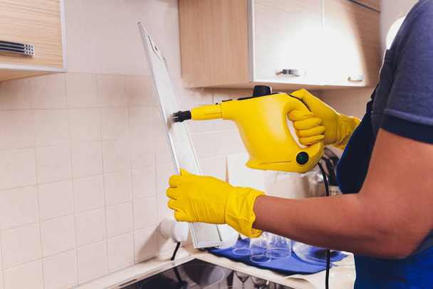 Professional janitor cleaning mesh filter of cooker hood in kitchen, closeup. - Foto, Bild