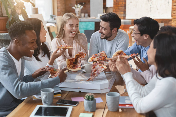 Щасливі люди їдять піцу в офісі під час обіду
 - Фото, зображення