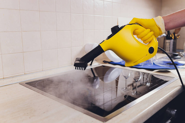 Cleaning kitchen hob with a steam cleaner. - Valokuva, kuva