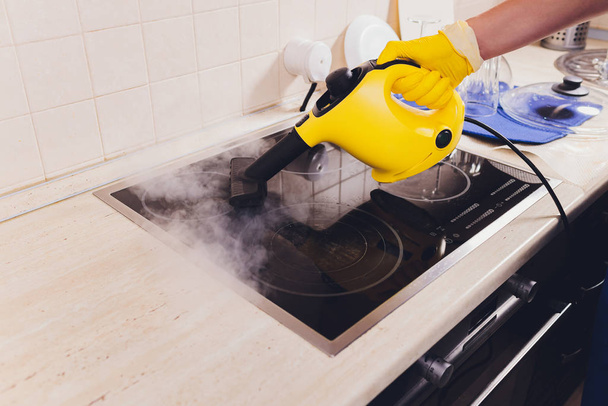 Cleaning kitchen hob with a steam cleaner. - Foto, afbeelding