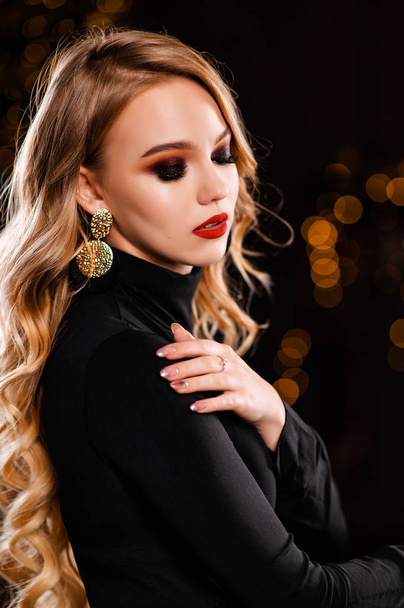 Blonde with curls and makeup on a black background - Foto, afbeelding
