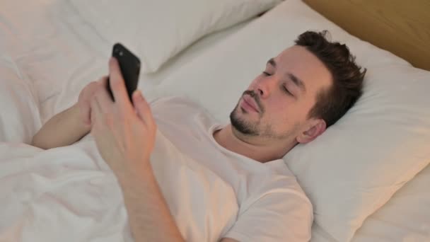 Young Man using Smartphone in Bed - Video, Çekim