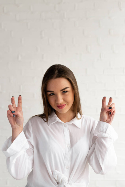 A young woman with long brown hair gesticulates with her fingers depicting quotes - Фото, зображення