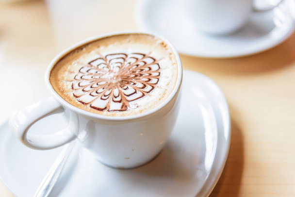 hete koffie op tafel / warme cappuccino met mooi patroon melkschuim  - Foto, afbeelding
