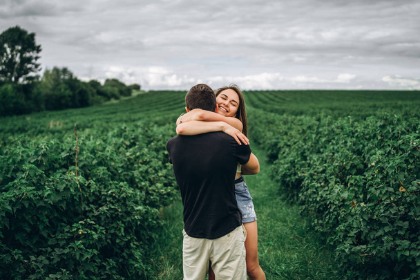 A tender loving couple walking in a field of currant. Man whirls - Foto, Imagen