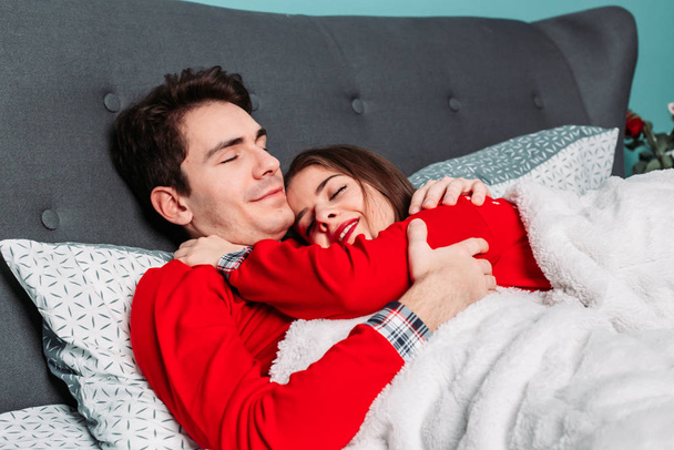 Couple lying in bed hugging and looking happy. Valentines day concept - Photo, image