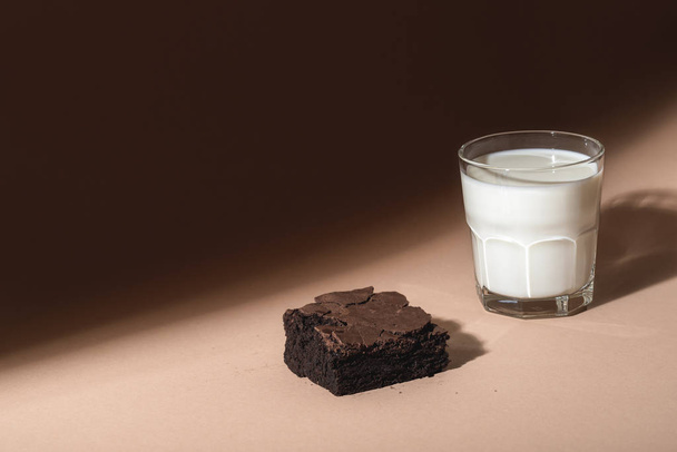 Glass of milk and brownie cookie in sunlight. Sweet breakfast  - Photo, image