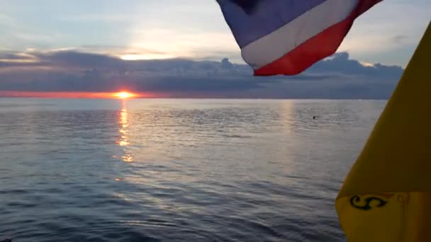 Boat floating with flags in evening. Thai and King of Thailand flags against cloudy sundown sky and romantic sea - Footage, Video
