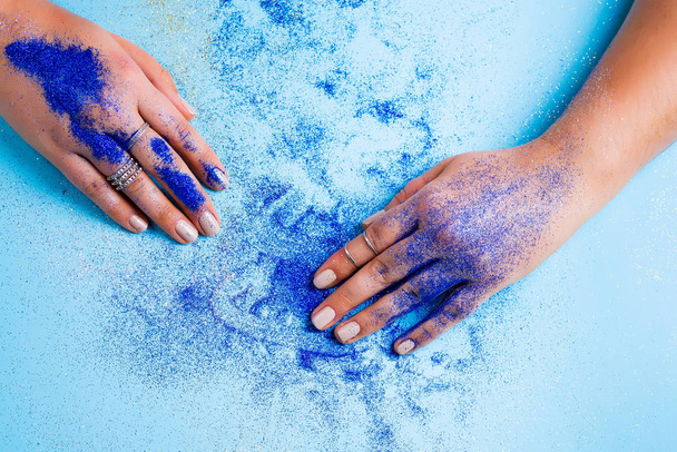 detail of womans hands painted in classic blue glitter dust on blue background - Φωτογραφία, εικόνα